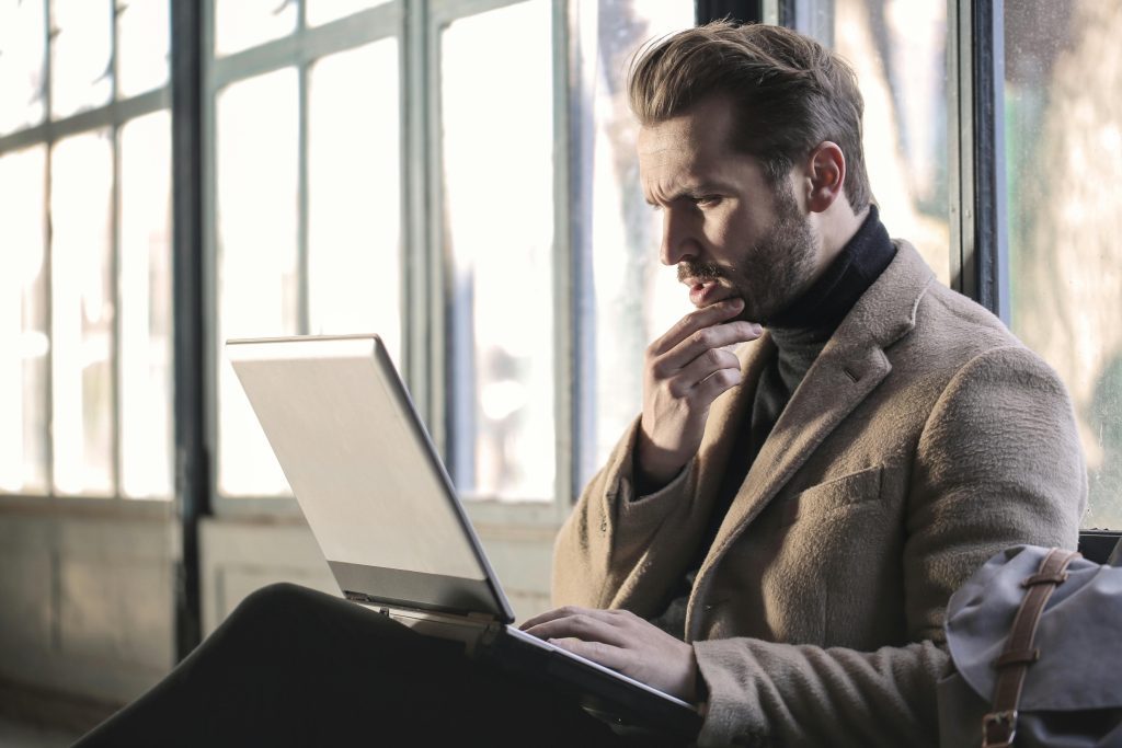 pexels-photo-874242-874242 Man looking contemplative while working on a laptop in a well-lit indoor space.